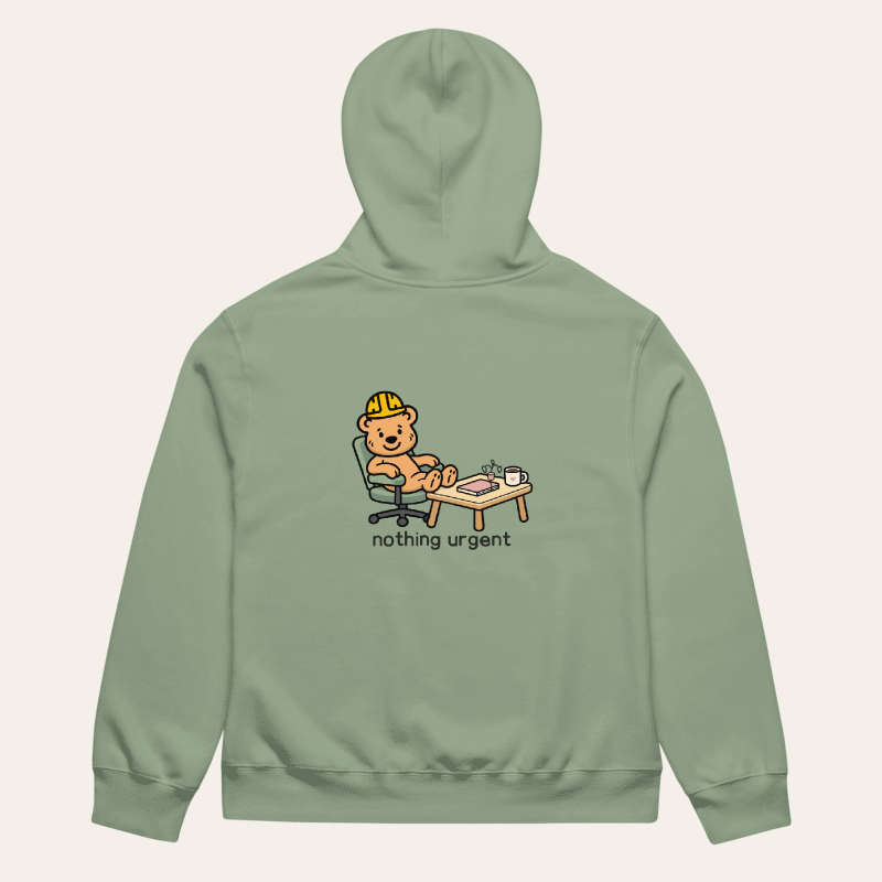 Sage Nothing Urgent hoodie laid flat, back view with Tee Bear desk and plant artwork
