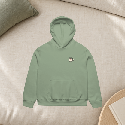 Sage Nothing Urgent hoodie front in a cream linen lifestyle flatlay mockup; styling props not included