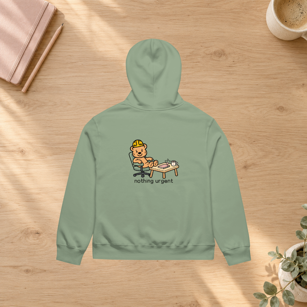 Sage Nothing Urgent hoodie back in a slow-morning desk flatlay mockup with notebook and plant; props not included