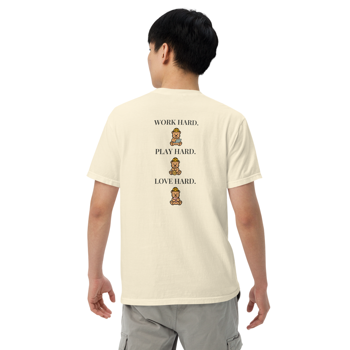 Model wearing the Ivory Work Hard Three Bears relaxed-fit T-shirt, showing the back slogan and three helmeted bears with a laptop, basketball, and heart.
